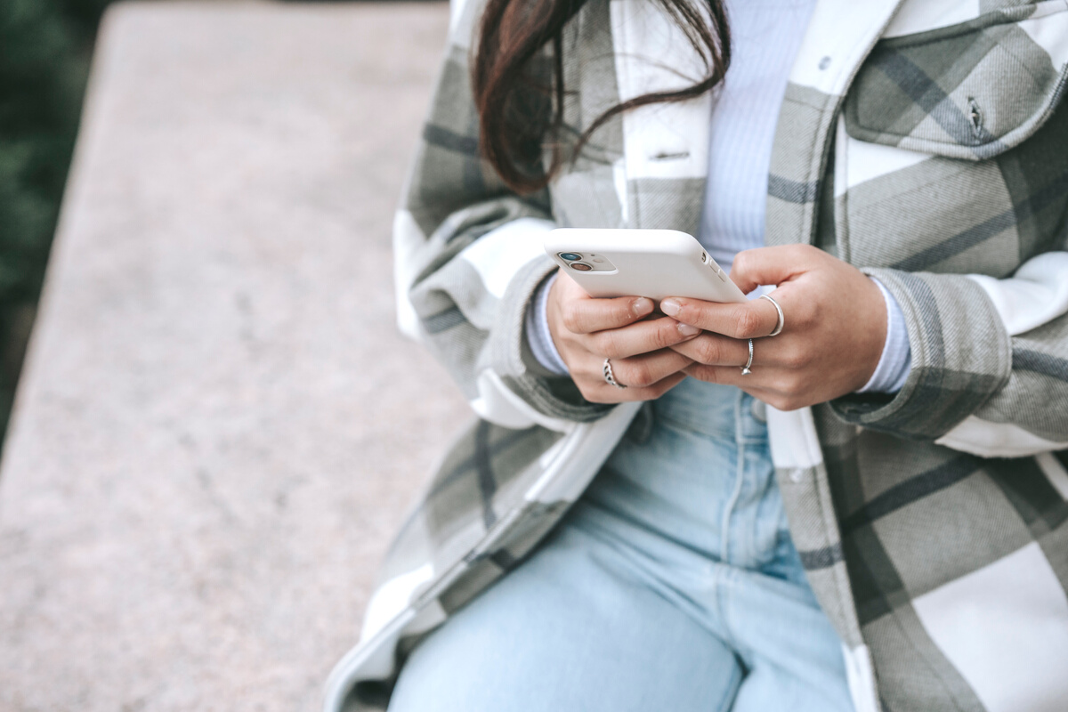 Faceless woman sitting in street with phone